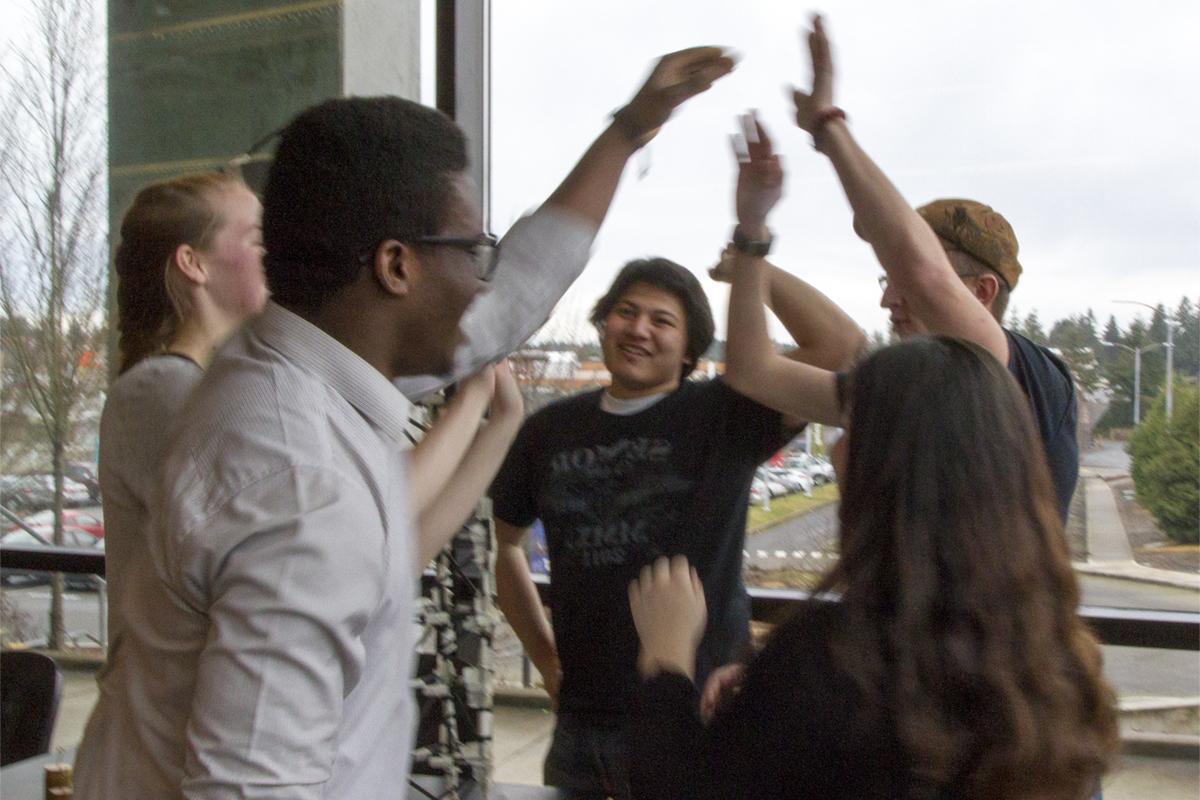 A group of students high fiving around a lab table