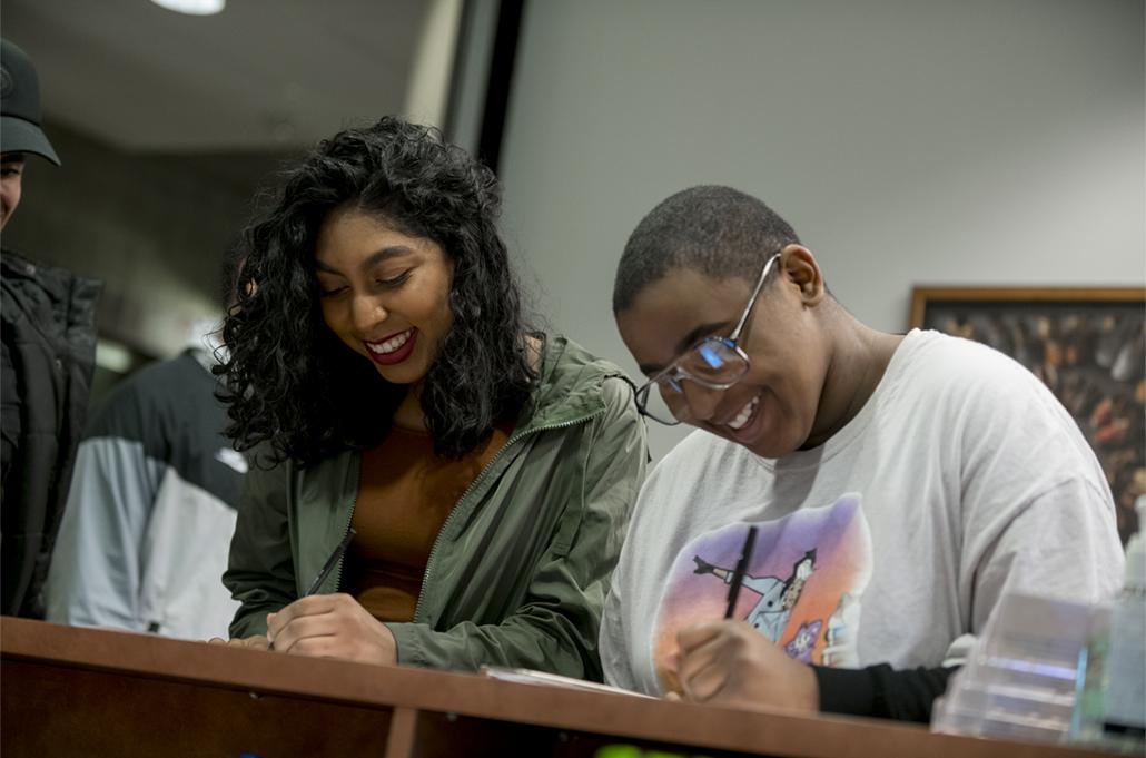 Two students at a desk writing